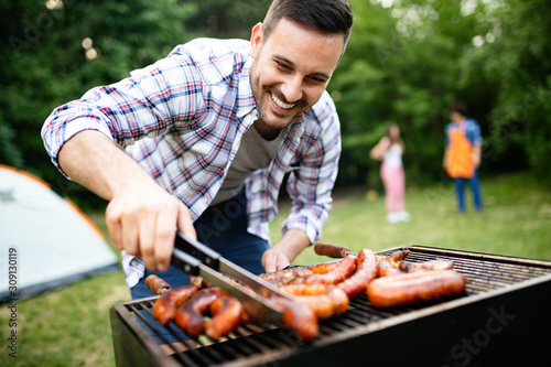 Man cooking meat on barbecue grill at outdoor summer party photo