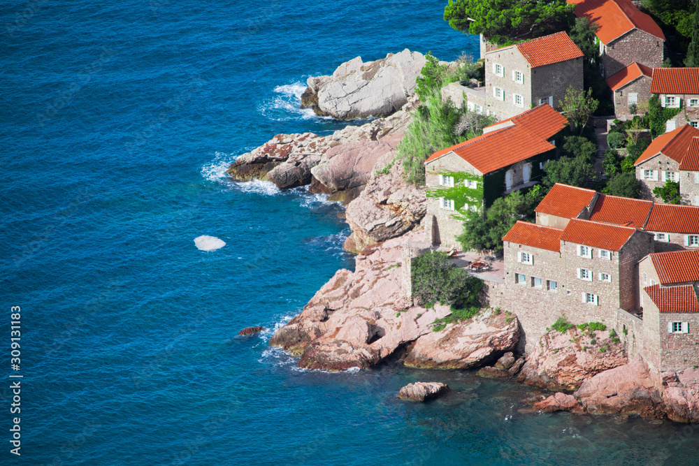 Mediterranean town.  houses with a tiled roof and green trees by the blue sea. happiness in relaxation in warm countries. Sveti Stefan