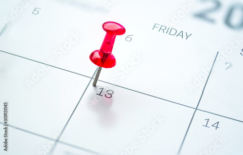 Red push pin on calendar friday the 13th day of the month