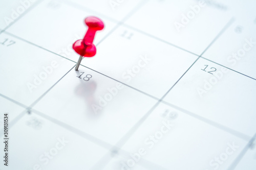 Red push pin on calendar 18th day of the month