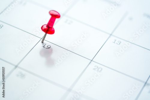 Red push pin on calendar 19th day of the month