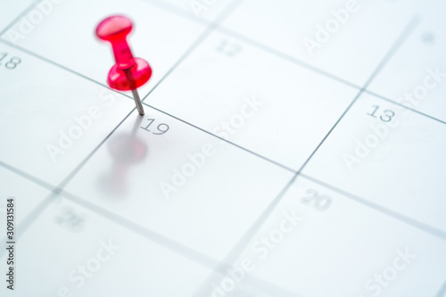 Red push pin on calendar 19th day of the month