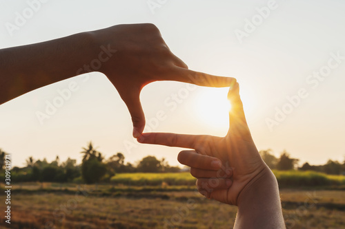 closeup hand framing view distant over sunset. business concept