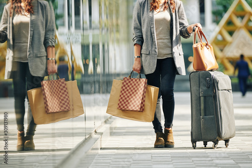 Cropped image of woman with big suitcase and many shopping bags after spending weekedn in big city photo