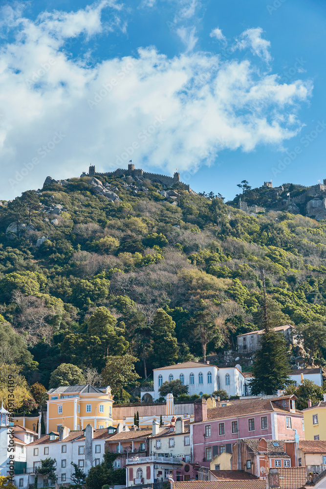 beautiful houses near a hill overgrown with forest with an old fortress on top in the Portuguese town of Sintra