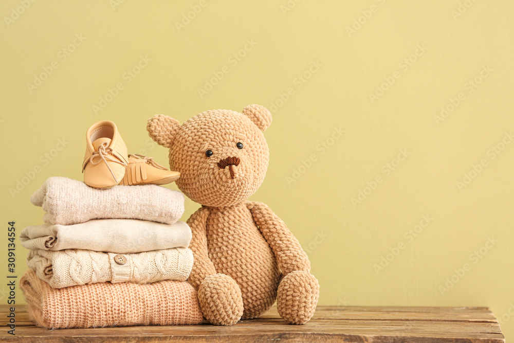 Stack of baby clothes and toy on table - obrazy, fototapety, plakaty 