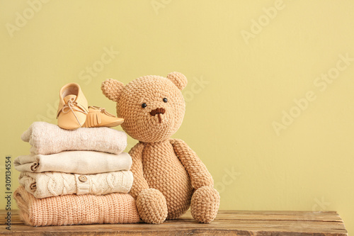 Stack of baby clothes and toy on table photo