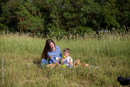 Beautiful mom with her son on a picnic rest in nature