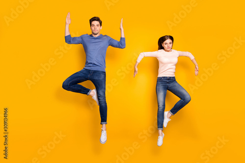 Full length photo of serious team married couple jump raise hands dance like humanoid robots wear stylish modern clothes isolated over bright color background