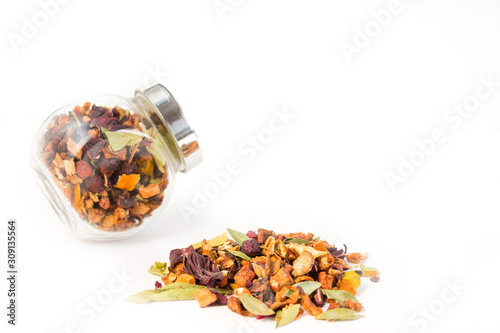 Fruit tea (tea leaves) in a glass jar and a scattered tea leaves bunch on a white background. Breakfast and tea party concept.