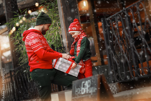 Family of two father and son are packing a gift box by tying it with a red ribbon