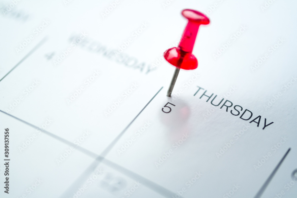 Red push pin on calendar 5th day of the month Red push pin on calendar 5th day of the month