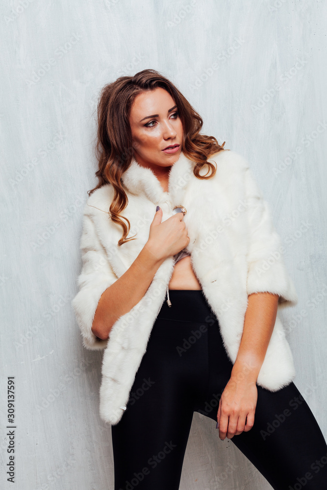 Portrait of a beautiful fashionable woman with hair curls in a white fur coat Portrait of a beautiful fashionable woman with hair curls in a white fur coat