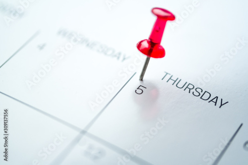Red push pin on calendar 5th day of the month