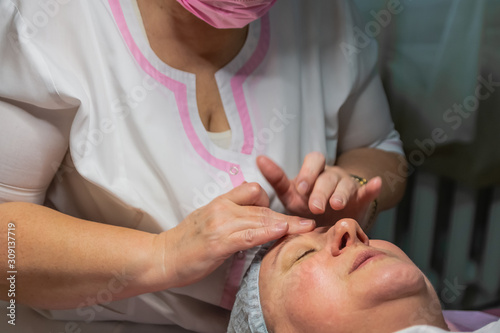 A cosmetic procedure with manual facial massage in a beauty salon is performed for an aged woman. Improving skin turgor  rejuvenation and healing.