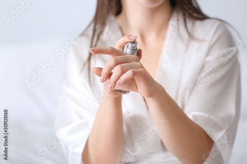 Young woman applying cosmetic serum on her skin at home