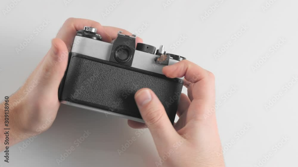An unrecognized man charges a new film into an old retro vintage camera. Closes the body cover and takes the first photo shot. An unrecognized man charges a new film into an old retro vintage camera. Closes the body cover and takes the first photo shot.