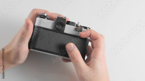 An unrecognized man charges a new film into an old retro vintage camera. Closes the body cover and takes the first photo shot.