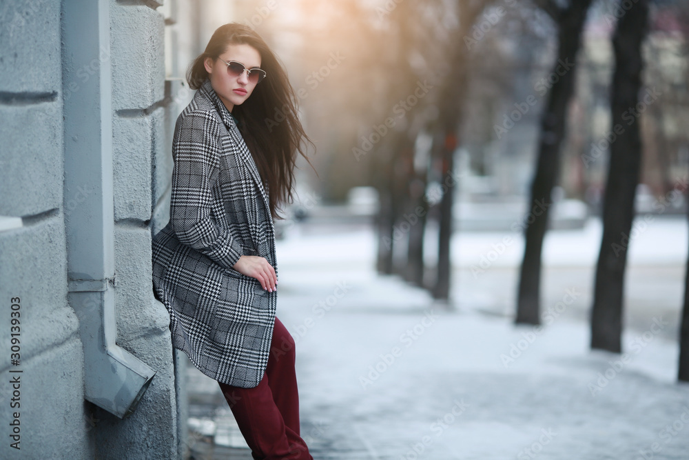 A woman stands on the street in winter near a building with white walls. A woman stands on the street in winter near a building with white walls.