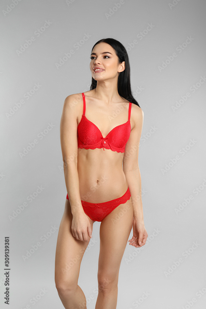Beautiful young woman in red underwear on grey background Beautiful young woman in red underwear on grey background