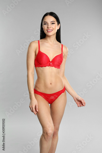 Beautiful young woman in red underwear on grey background