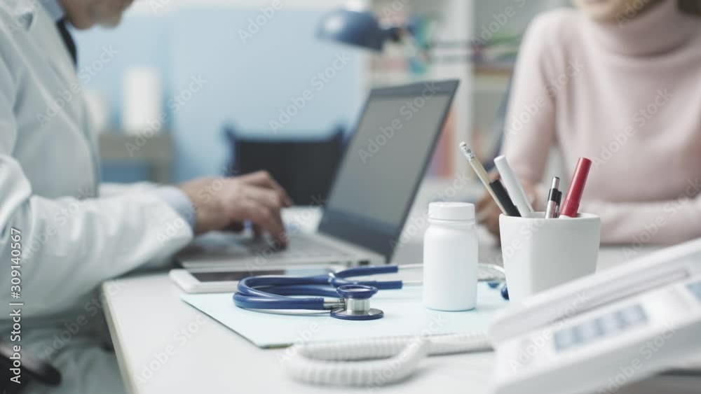 Doctor meeting a patient and typing with a laptop