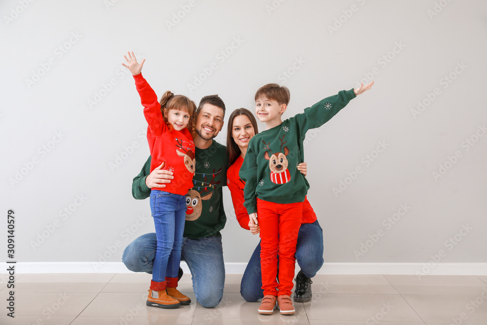 Obraz premium Happy family in Christmas clothes near light wall