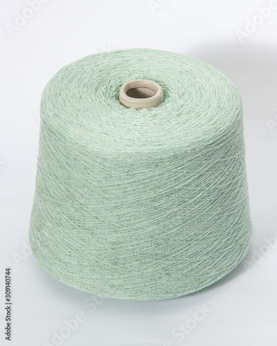 Green bobbin of yarn on a white background.Textile reel on isolated white background.