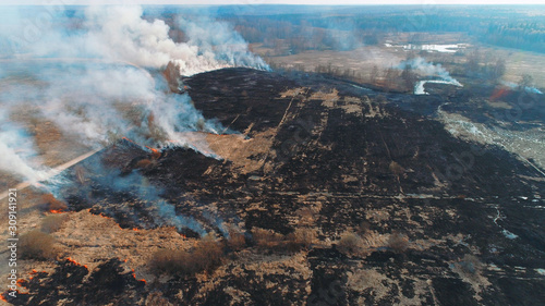 Forest and field fire. Dry grass burns  natural disaster. Aerial view. Large field fire with many places of burning.