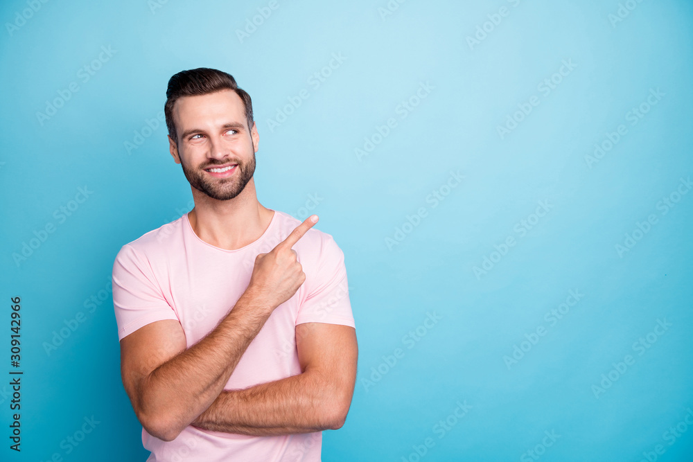 Photo of funny guy indicating finger empty space advising cool low discount prices best quality products wear casual pink t-shirt isolated blue color background Photo of funny guy indicating finger empty space advising cool low discount prices best quality products wear casual pink t-shirt isolated blue color background