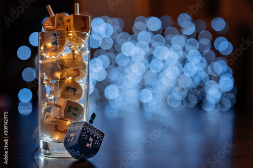 Vászonkép jewish holiday Chanukah/Hanukkah with wooden dreidels / sovivon (spinning top) in the glass over glitter shiny background