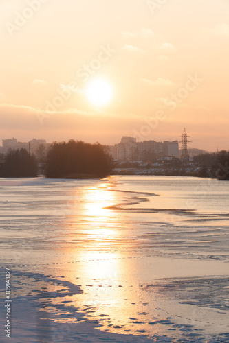sunset over a river covered in ice and snow