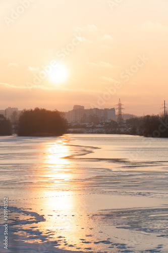 sunset over a river covered in ice and snow © ShevarevAlex