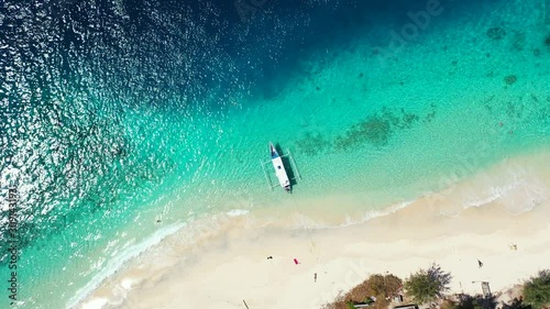 tropical vacation background. small fishing boat, white sand beach clear turquoise seawater, aerial photo