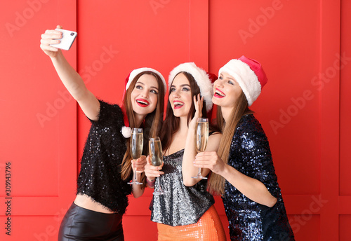 Canvas Print Beautiful young women with champagne taking selfie at Christmas party