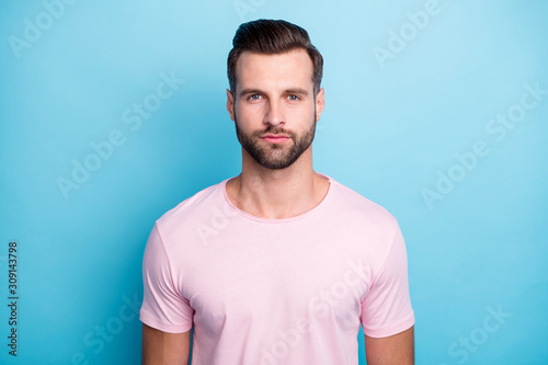 Close up photo of amazing macho guy standing not smiling looking seriously on camera wear casual pink t-shirt isolated over bright blue color background