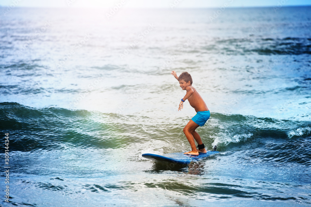 Little boy balancing on the surf board in sea Little boy balancing on the surf board in sea