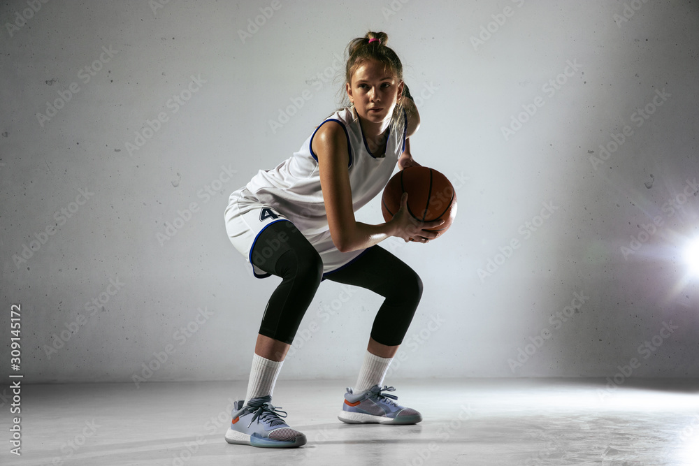 Young caucasian female basketball player of team in action, motion in run isolated on white wall background. Concept of sport, movement, energy and dynamic, healthy lifestyle. Training, practicing.