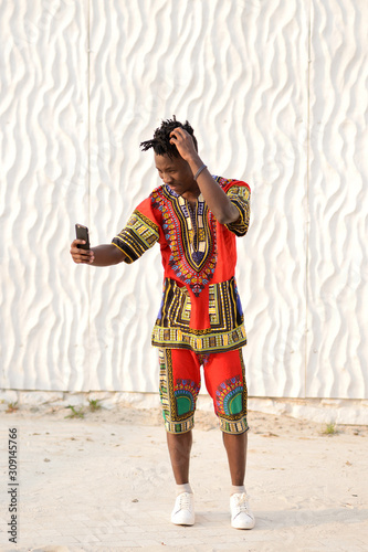 African American guy in national clothes on a background of a white wall