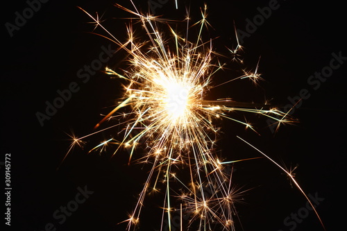 Christmas and New Year s illumination. Burning sparklers scatter bright exploding strips of sparks on a dark background.