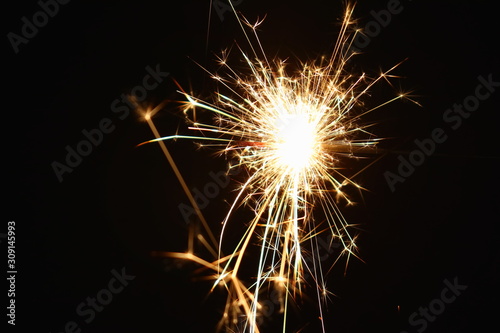 Christmas and New Year s illumination. Burning sparklers scatter bright exploding strips of sparks on a dark background.