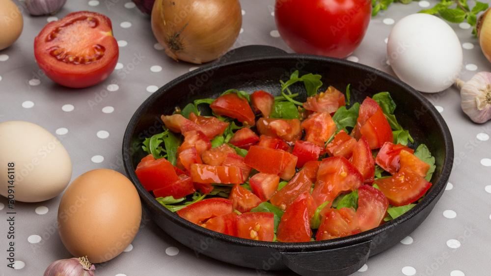 Eggs, olives, garlic on the table. Sliced tomatoes in a pan. .
