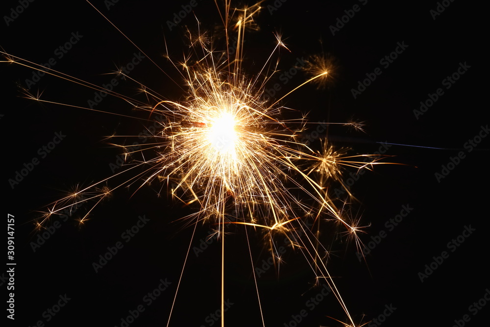 Christmas and New Year's illumination. Burning sparklers scatter bright exploding strips of sparks on a dark background.