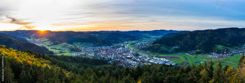 Germany, XXL aerial panorama view above black forest village haslach im kinzigtal and endless nature landscape over tree tops at sunset in autumn season