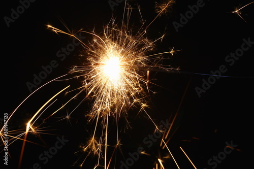 Christmas and New Year s illumination. Burning sparklers scatter bright exploding strips of sparks on a dark background.