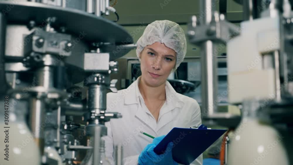 Woman Quality Control A woman checks bottles with milk, moving on a conveyor. Quality control ...