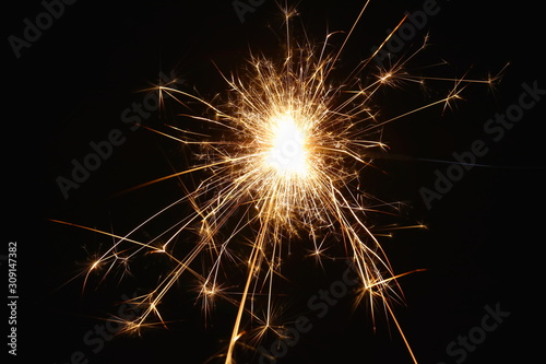 Christmas and New Year s illumination. Burning sparklers scatter bright exploding strips of sparks on a dark background.