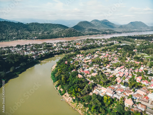 Luang Prabang, Laos. Aerial view of Luang Prabang town in Laos. Cloudy sky over the small city surrounded by mountains. Car traffic and river photo