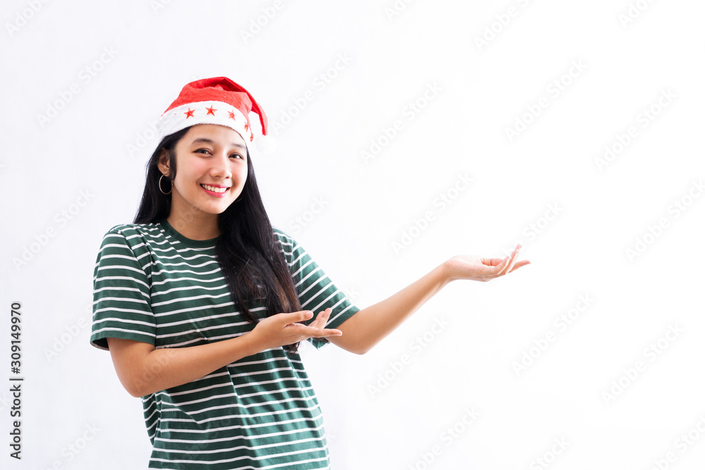 portrait of young Asian woman wearing a santa hat and wearing casual clothes presents a copy space on the left portrait of young Asian woman wearing a santa hat and wearing casual clothes presents a copy space on the left