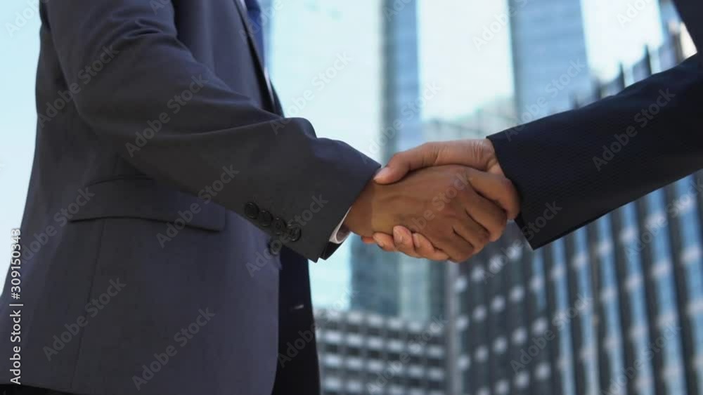 Slow motion of business partners making handshake against corporate building background in the city for mergers and acquisitions concept